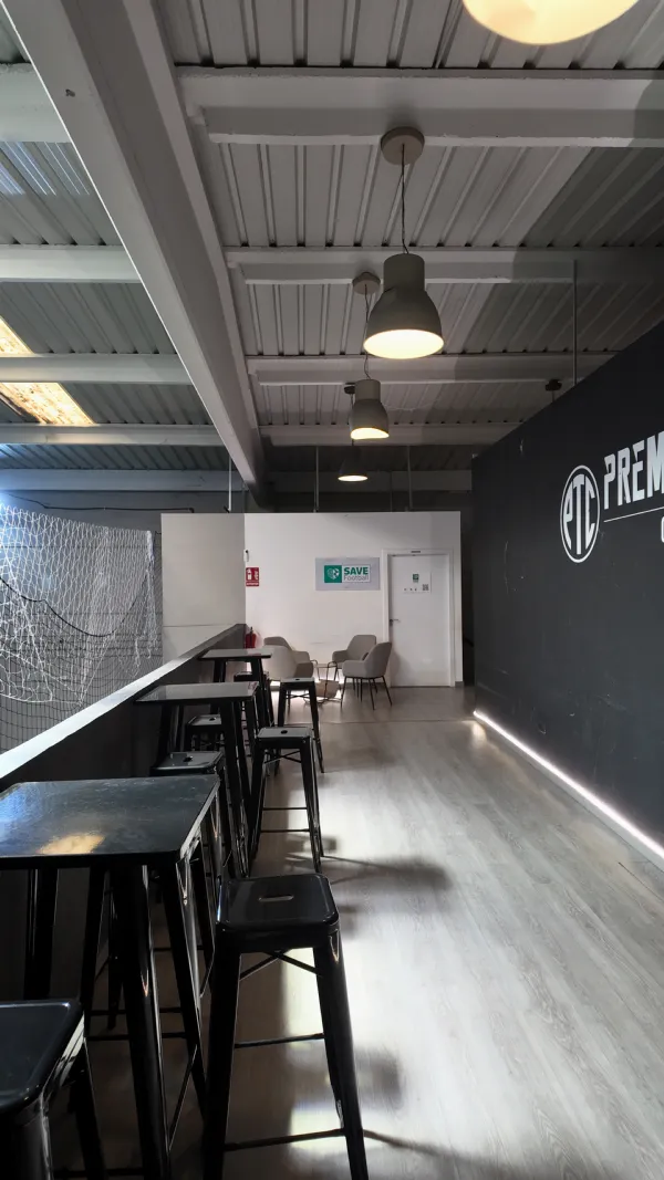 Zona social con mesas altas junto al campo de fútbol indoor, ideal para cumpleaños en Madrid
